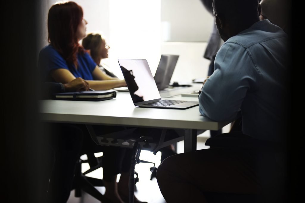 Grupo de pessoas reunido em uma sala de trabalho com notebooks