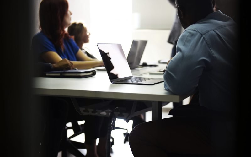 Grupo de pessoas reunido em uma sala de trabalho com notebooks
