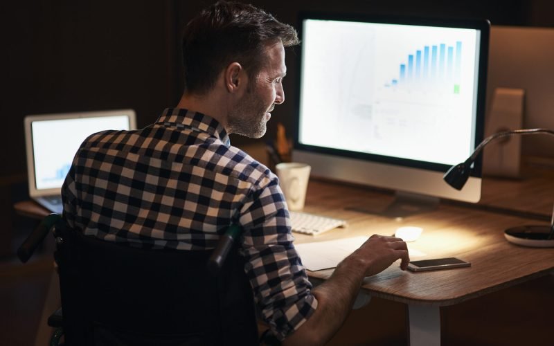 Homem trabalhando à noite diante de gráficos de dados no computador